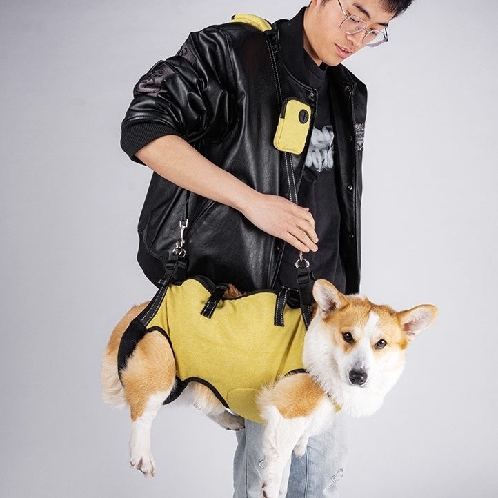 a small dog wearing a yellow Dog Lift Harness and Backpack Carrier, carried on the owner's shoulder