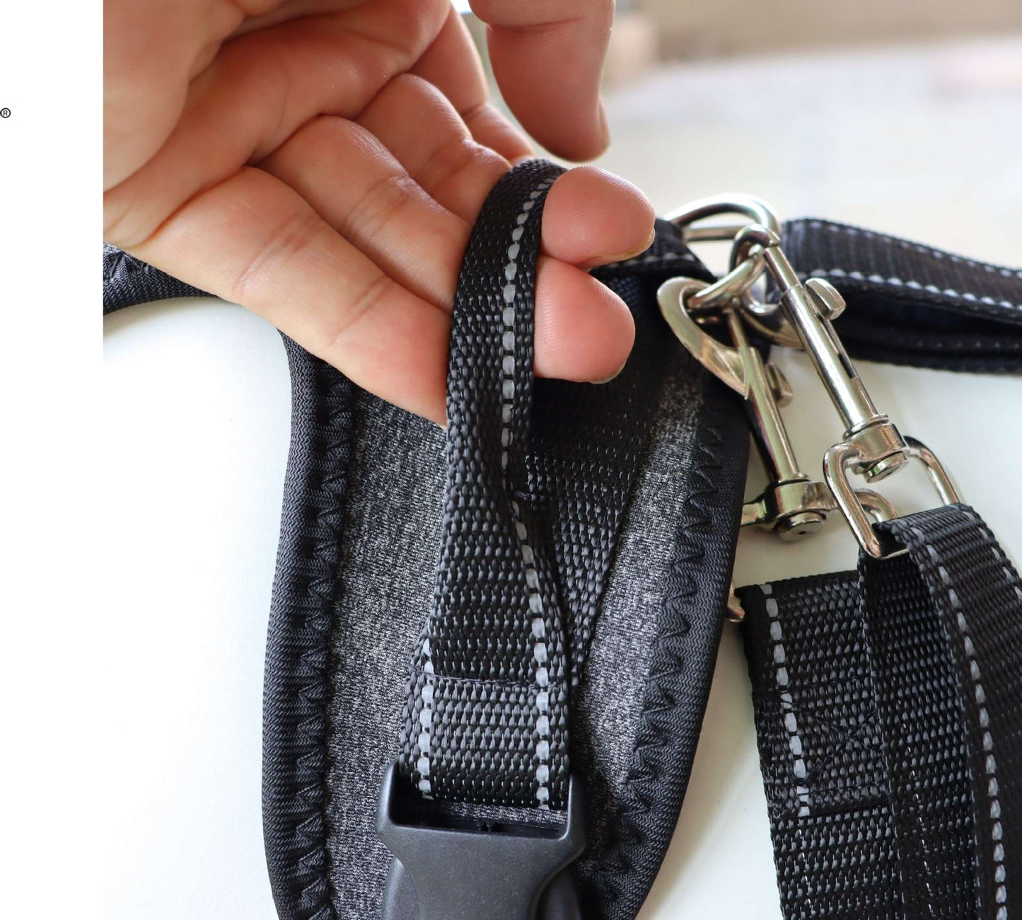 Close-up of a black dog leash of Full-Body Split Lifting Support harness with a metal clip held by a hand.