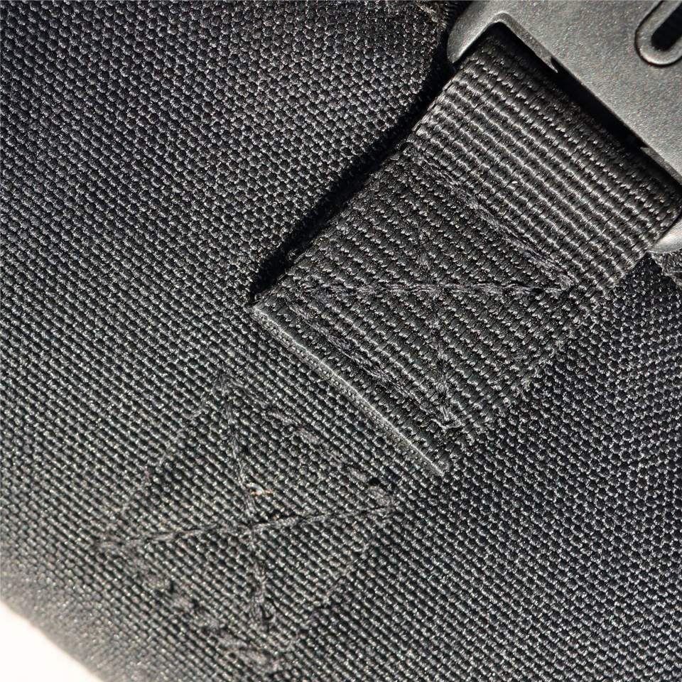 Close-up of a black strap with a textured surface and visible stitching on a gray background.